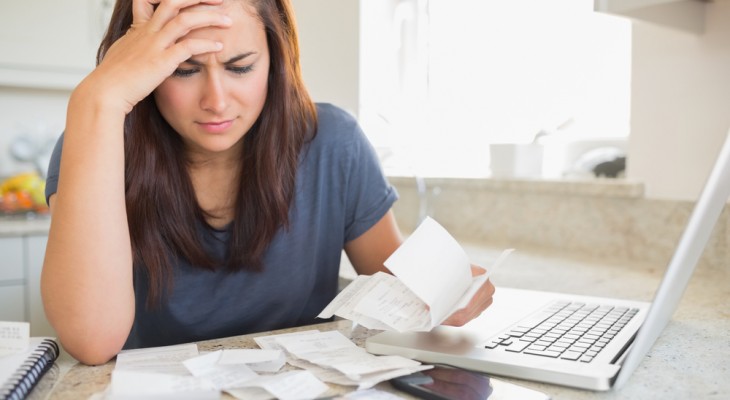 Woman sat at the table, worried looking at her bills