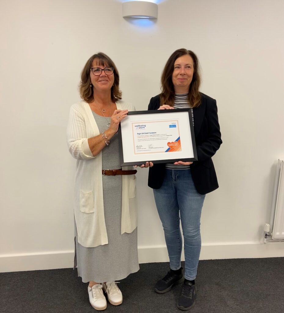 Two employees from Age UK holding their Commitment Award certificate.