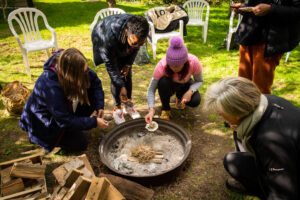 People around a fire pit, lighting up a fire