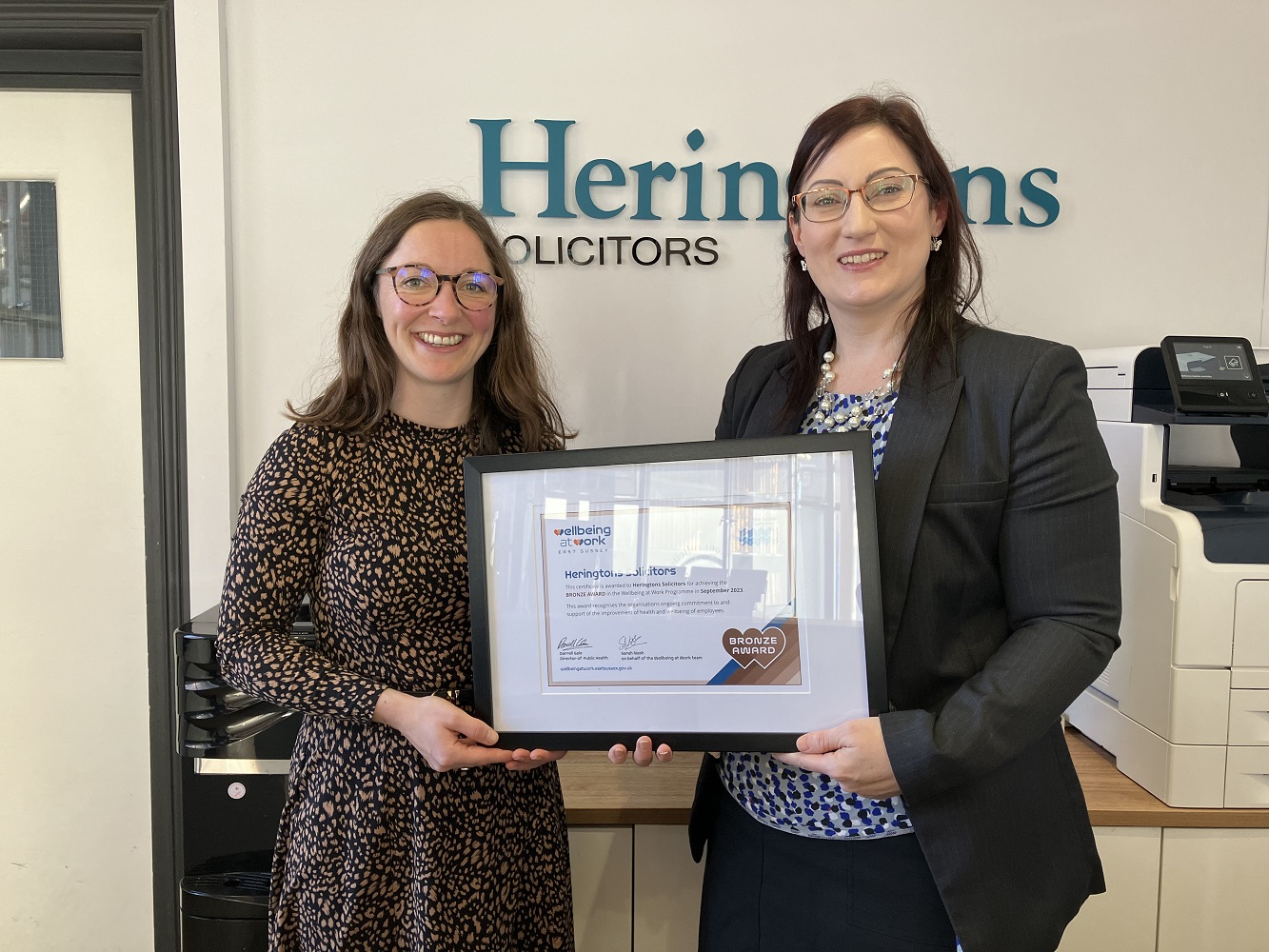 ESCC staff handing over framed certificate of wellbeing award to Heringtons' employee
