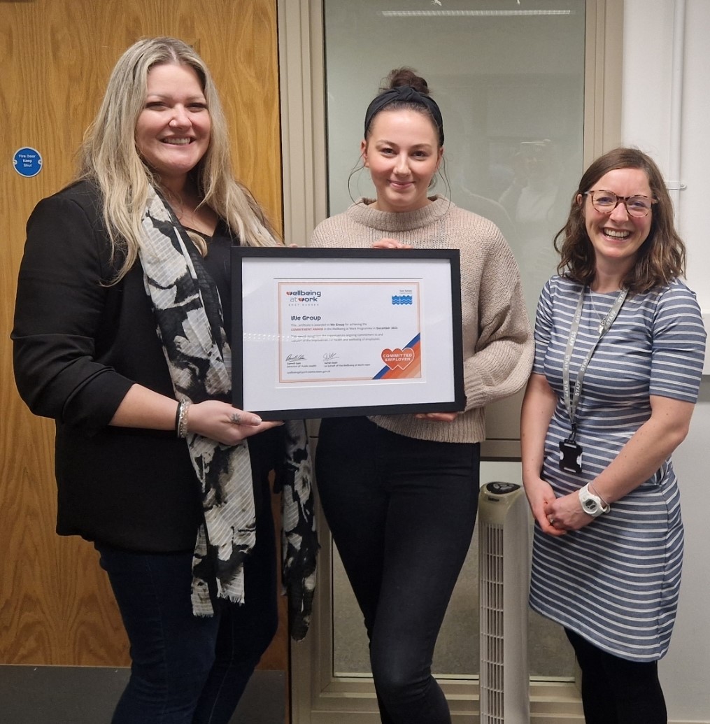We Group staff with Wellbeing at Work team holding their framed Commitment Award certificate